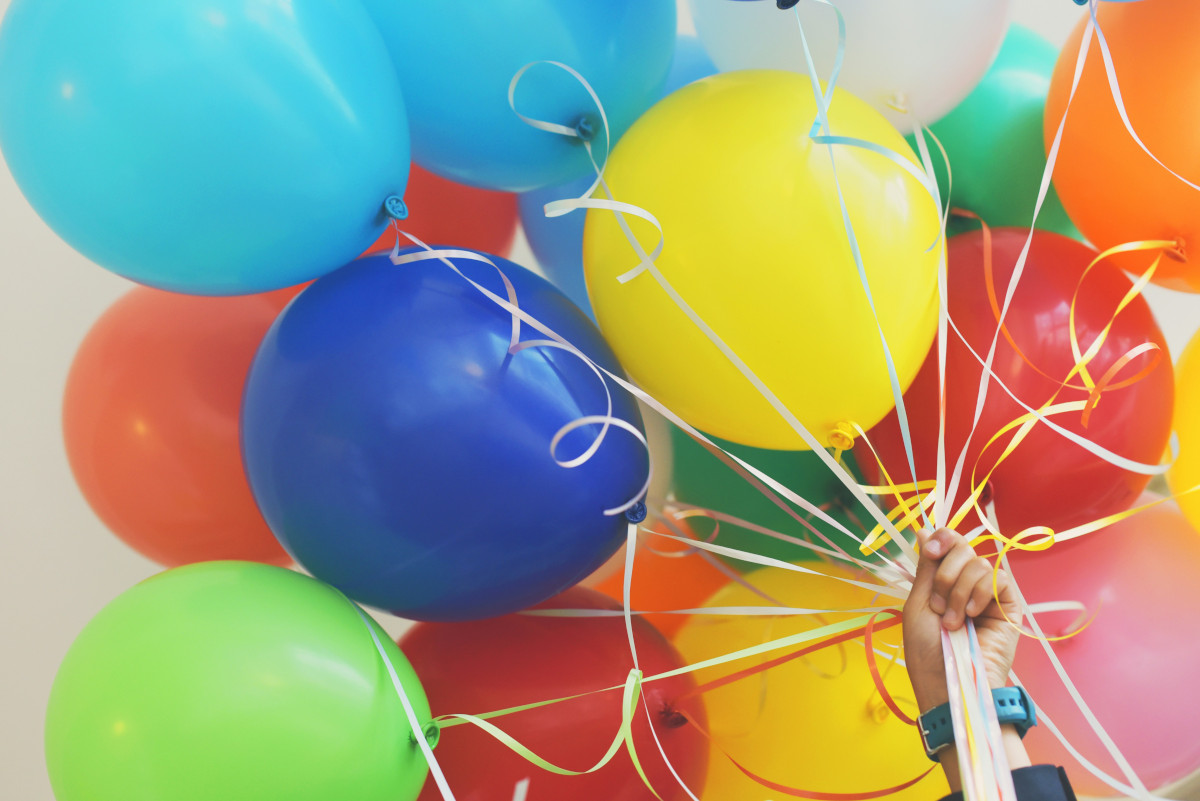 A hand holding a bunch of party balloons